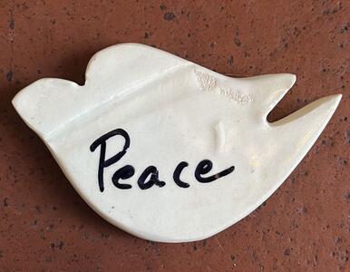  a white ceramic dove with the word “Peace” written in black paint created by a Core Member of L’Arche Jacksonville}
